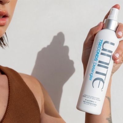 Model holds Unite 7Seconds Detangler leave-in conditioner bottle, emphasizing smooth, conditioned hair with professional salon results