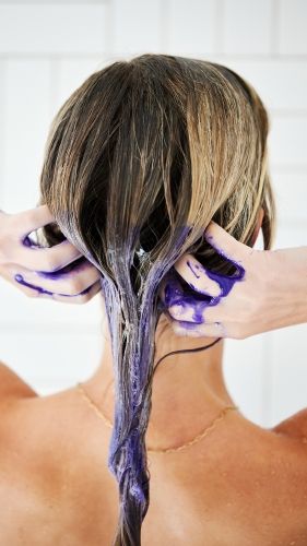 Hands apply purple toning treatment through wet blonde hair in the shower, illustrating color correction and care with UNITE Hair