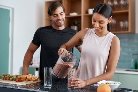 Couple preparing a healthy chocolate smoothie together in a modern kitchen