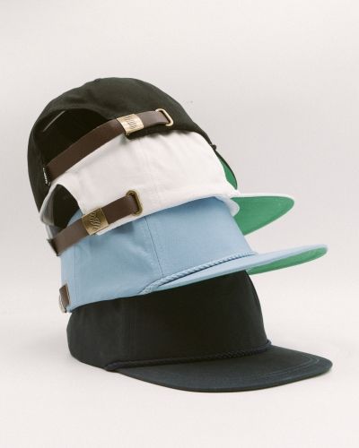 Stack of premium snapback caps in black, blue, and white colorways