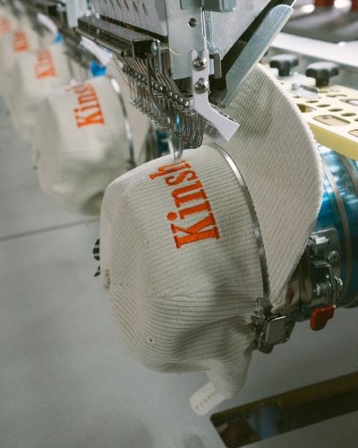 Embroidery machine stitching custom logo onto cream knit beanie at SNAG Collective