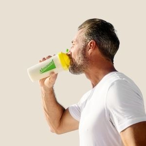 Man enjoying a protein shake from an Almased shaker bottle after fitness activity
