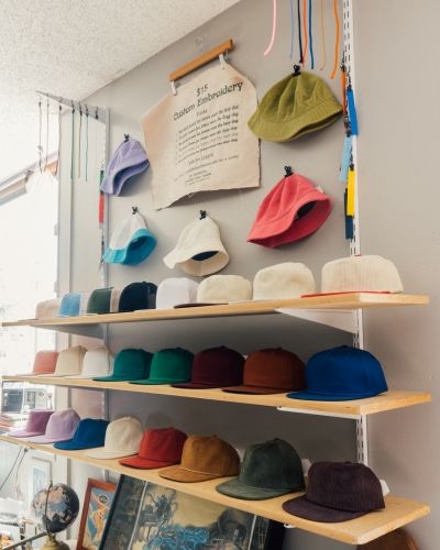 Colorful custom hats and bucket hats displayed on retail shelves inside SNAG Collective showroom