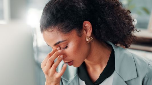 Woman experiencing eye strain and fatigue while working indoors.