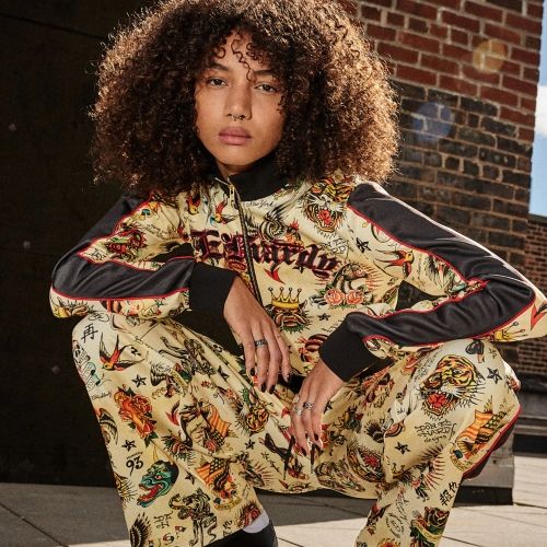 Model in a tattoo-inspired Ed Hardy tracksuit with colorful graphic artwork and black sleeve details
