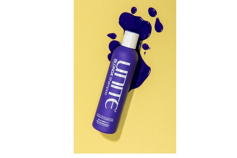 UNITE BLONDA violet toning shampoo bottle on yellow surface with spilled purple liquid highlighting product