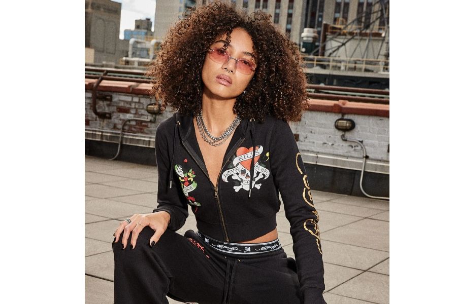 Person in black cropped Ed Hardy hoodie with skull heart Love Kills Slowly design, pink sunglasses, silver chains
