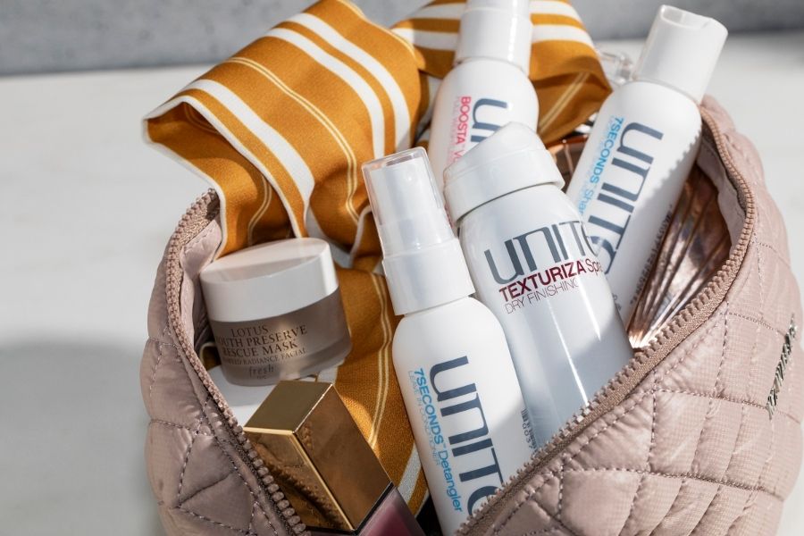 Beige quilted bag with UNITE Hair sprays and Fresh Lotus mask neatly arranged among premium beauty essentials