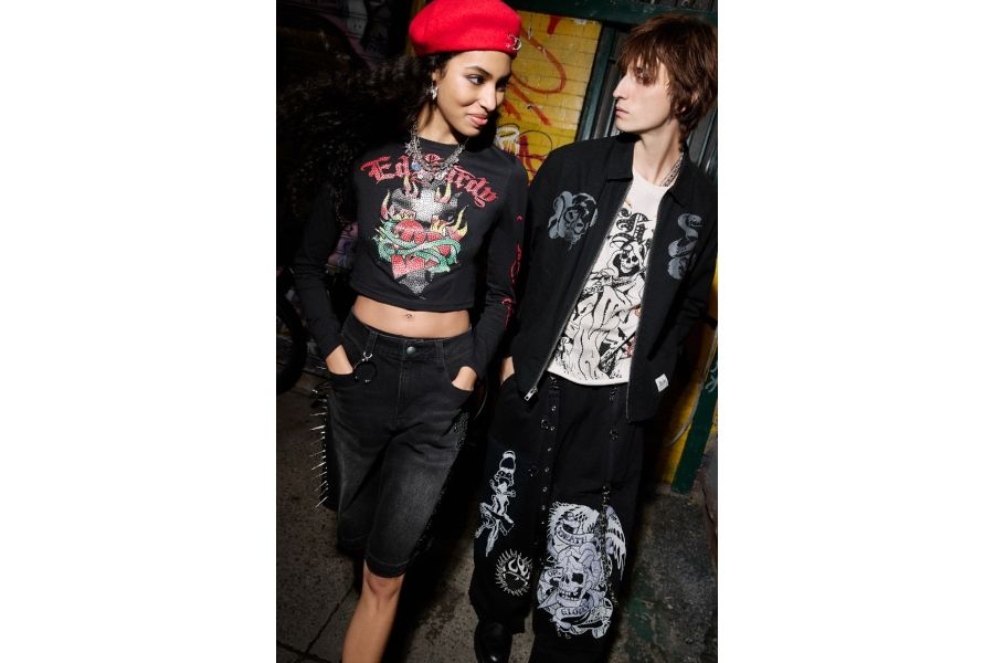 Ed Hardy streetwear with flaming heart crop top and skull graphic jacket styled in urban graffiti backdrop setting