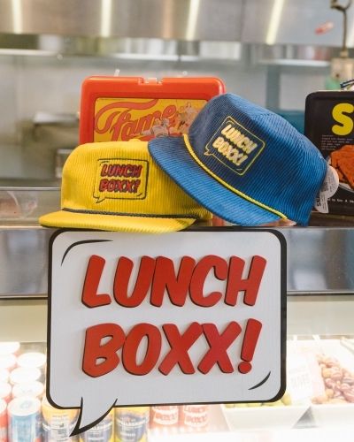 Lunch Boxx display with custom corduroy hats and branded lunchbox in retail shop