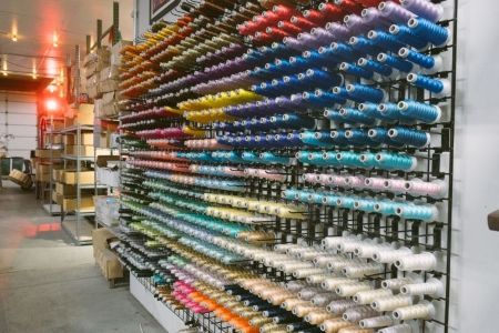 Colorful embroidery thread spools organized in a custom hat production workshop