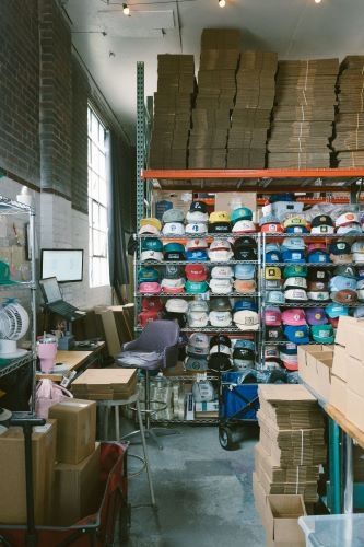 Warehouse shelves stocked with custom snapback hats and packaging supplies for fulfillment