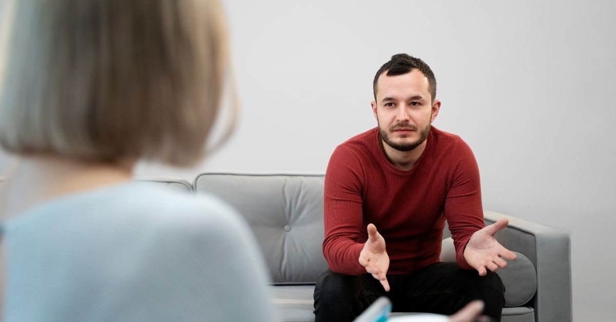 Young man speaking open-handedly with a therapist during a counseling session